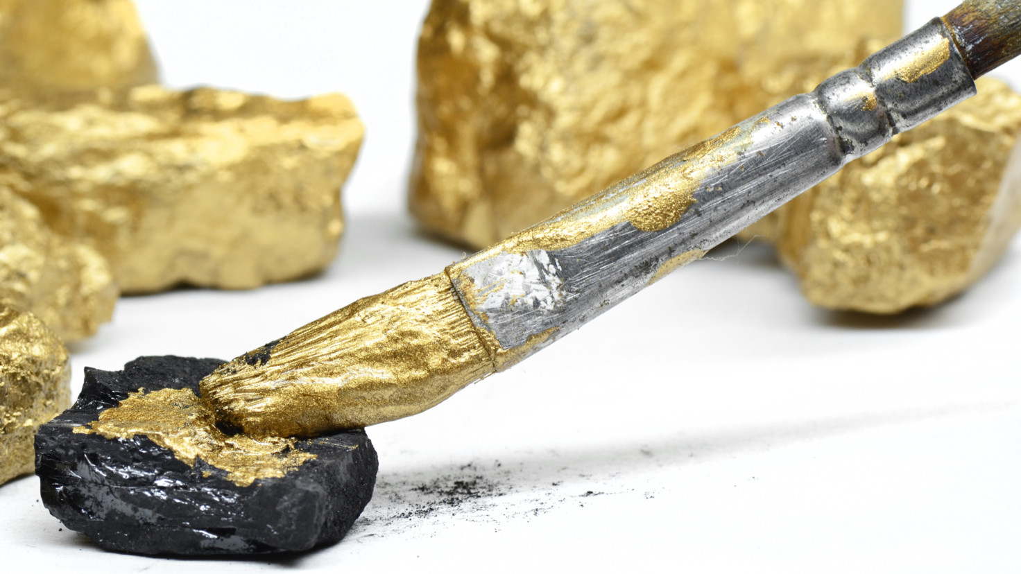 Fake gold paint being applied to black rocks